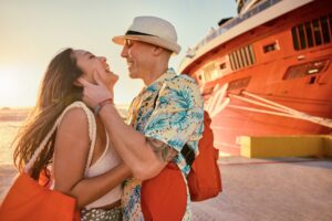 A couple smiles in front of the aft of Valiant Lady during sunset. Lifestyle imagery